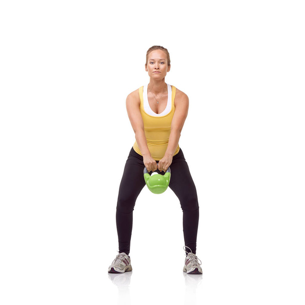 Swinging her kettlebell. A beautiful blonde woman performing a two-handed kettlebell swing - Zdjęcie, obraz
