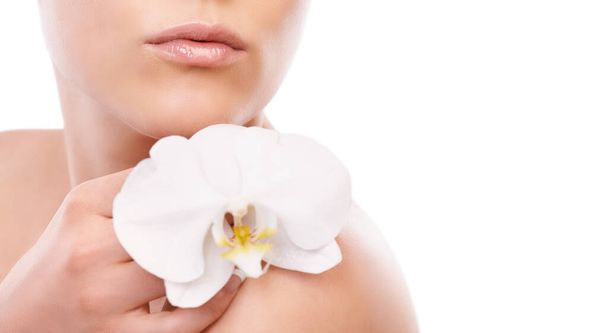 Doğanın özünün cildini canlandırmasına izin ver. Bir kadının çıplak omzunda duran bir orkidenin kırpılmış görüntüsü. - Fotoğraf, Görsel