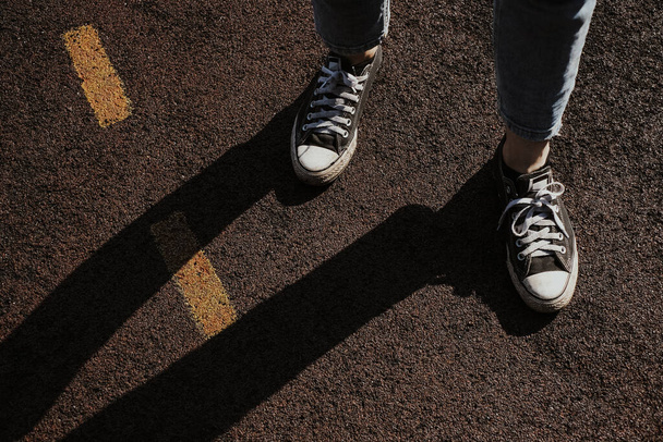 Chica en jeans y zapatillas blancas y negras de pie en un parque infantil de baloncesto con rayas amarillas. - Foto, Imagen
