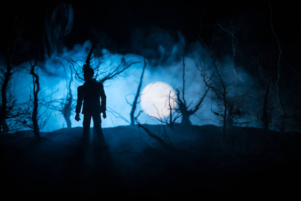 Silhouette einer Person, die im dunklen Wald steht. Horror-Halloween-Konzept. Seltsame Silhouette in einem dunklen Gruselwald bei Nacht - Foto, Bild