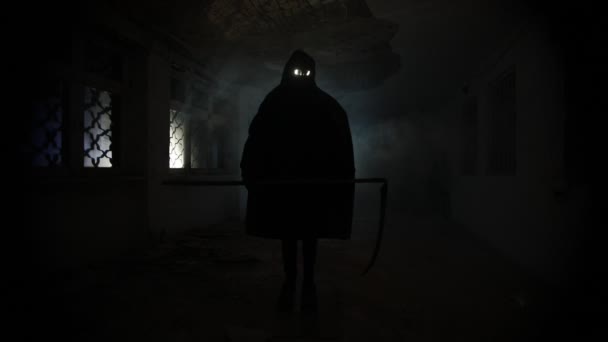 Tod mit einer Sense, die in der dunklen Halle steht. Horror-Silhouette in der Bauruine - Filmmaterial, Video