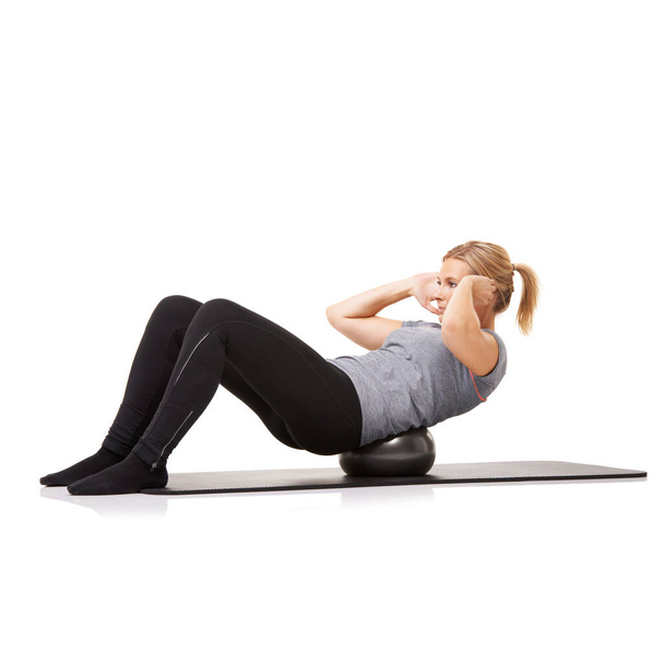 Crunches with an exercise ball. A young woman doing sit-ups on an exercise ball while isolated on a white background - Foto, Imagem