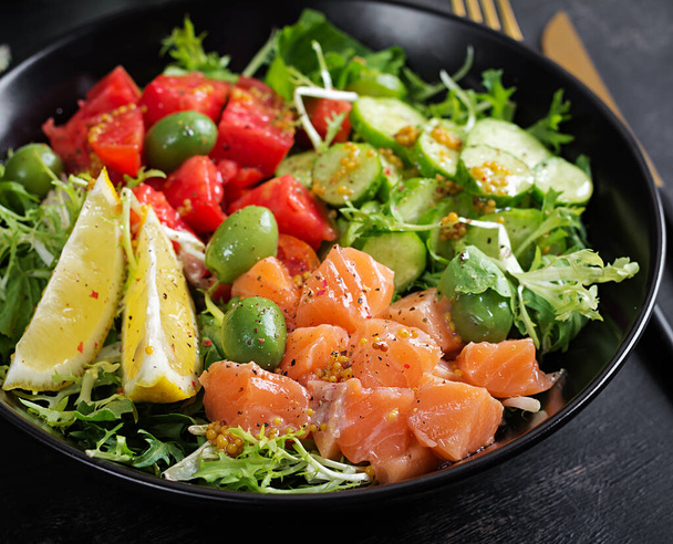 Ketogenic, keto or paleo diet lunch bowl with salted salmon fish, lemon, cucumber, olives, tomatoes, green lettuce salad and honey mustard dressing. Healthy food trend. - Photo, Image