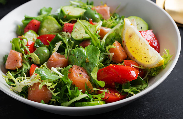Ketogenic salad with salted salmon fish, lemon, cucumber, olives, tomatoes, green lettuce salad and honey mustard dressing. Healthy food trend. - Photo, Image