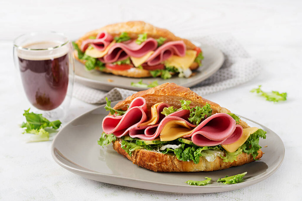 Croissant fresco ou sanduíche com salada, presunto e queijo sobre fundo claro. - Foto, Imagem