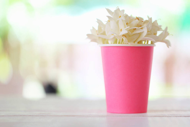 Kwiat Kasalong lub Millingtonia hortensis kwitnie w papierowej filiżance na drewnianym tle podłogi i mają przestrzeń do kopiowania. - Zdjęcie, obraz