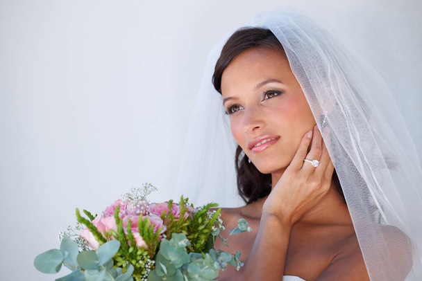She looks fantastic on her big day. A gorgeous young bride holding her bouquet - Фото, изображение