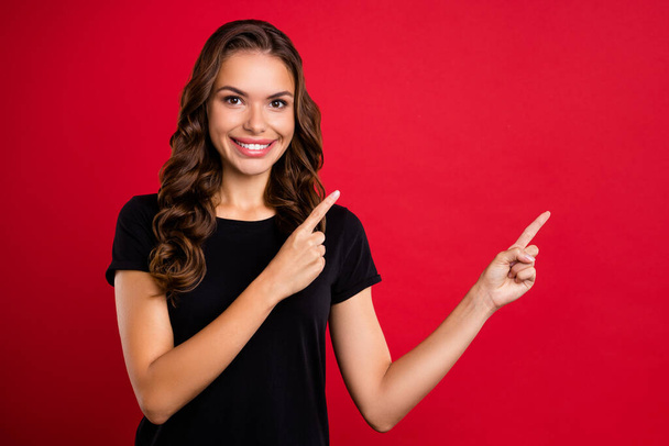Photo of young pretty girl indicate fingers empty space ads direct way suggest isolated over red color background. - Фото, изображение