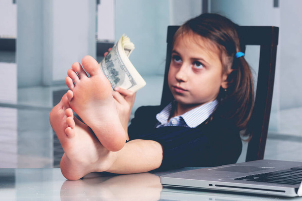 Humorous portrait of happy cute young business girl counts money profit. Selective focus on bare feet. Horizontal image. - Photo, Image