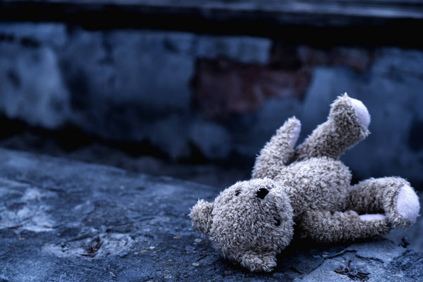 Dirty teddybeer speelgoed ligt buiten op de weg als symbool van eenzaamheid, pijn, verlies jeugd en toekomst van kinderen. Horizontaal beeld. Copyspace voor tex of design. - Foto, afbeelding
