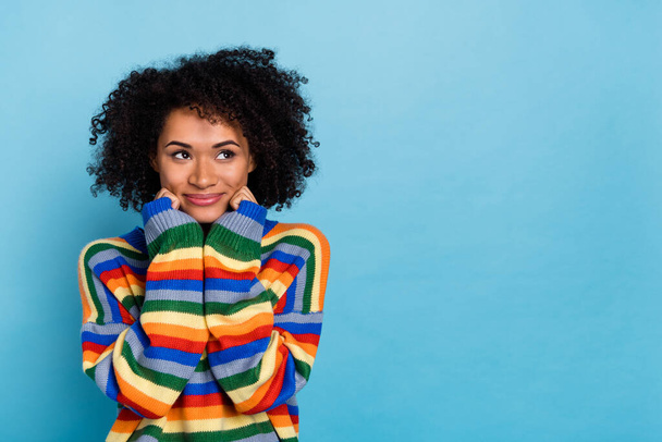 Photo of young curly hairdo lady hands face look promo wear colorful sweater isolated on blue color background. - Zdjęcie, obraz