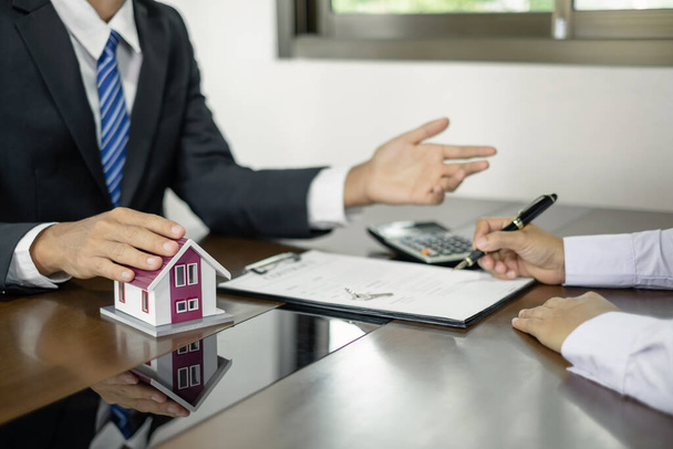 Immobilienmakler bieten eine Hausratversicherung an und schließen den Verkauf sofort ab, nachdem der Kunde einen Kaufvertrag im Rahmen einer formellen Vereinbarung unterzeichnet hat. Immobilien Eigenheimversicherungskonzept. - Foto, Bild