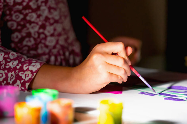 Kunst, aktiver Lebensstil und kreatives Konzept. Kinderhandmalerei mit Pinsel und bunten Farben. Selektiver Fokus auf der Hand. - Foto, Bild