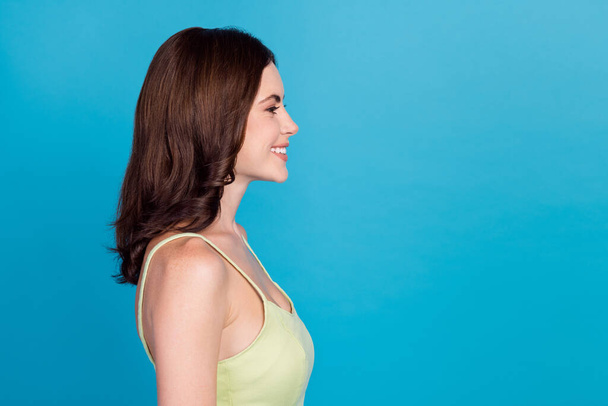 Profile portrait of cheerful gorgeous girl beaming smile look empty space isolated on blue color background. - 写真・画像