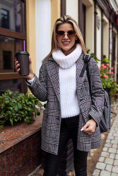 κομψή γυναίκα Τουριστικό περπάτημα γύρω από την πόλη με ένα φλιτζάνι καφέ. - Φωτογραφία, εικόνα