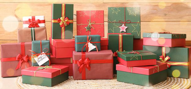 Many Christmas gifts on floor near wooden wall - Photo, Image