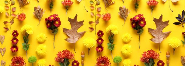 Many autumn leaves and chrysanthemum flowers on yellow background, top view - Valokuva, kuva