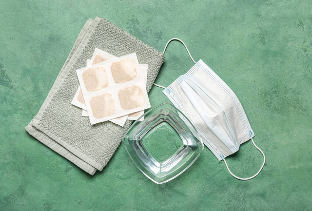 Mustard plasters with towel, bowl of water and medical mask on green background - Photo, Image