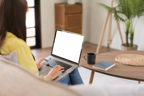 Concepto de actividad en el hogar, Mujer joven está charlando con amigos en el ordenador portátil mientras está sentado en el sofá. - Foto, imagen