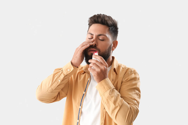 Homem barbudo jovem com sangramento nasal e tecido no fundo claro - Foto, Imagem