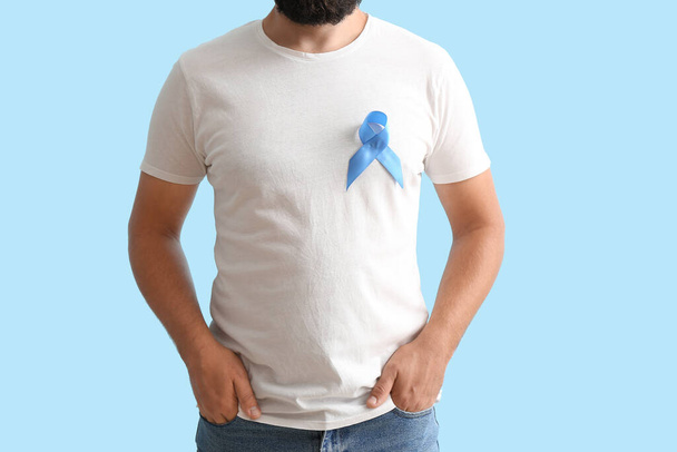 Homme avec ruban de sensibilisation bleu sur fond de couleur. Concept de cancer de la prostate - Photo, image