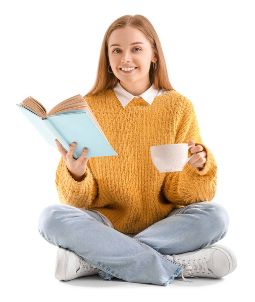 Jeune femme avec livre et tasse de cacao chaud assis sur fond blanc - Photo, image