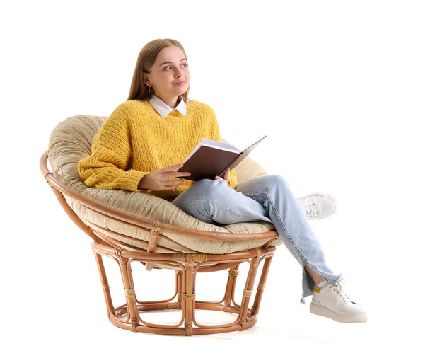 Mujer joven con libro sentado en sillón sobre fondo blanco - Foto, imagen