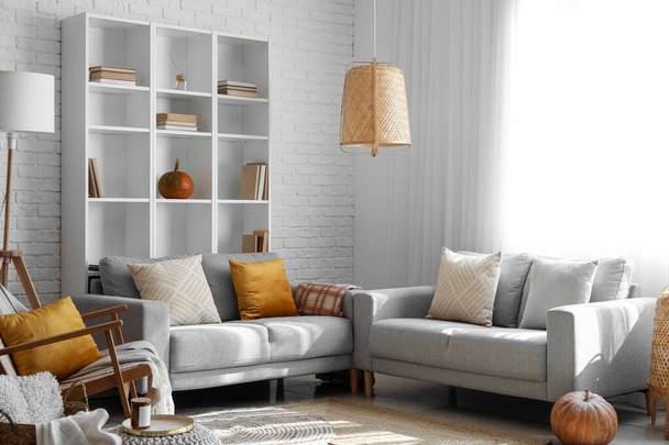 Interno del moderno soggiorno con divani grigi, scaffalature e zucche - Foto, immagini