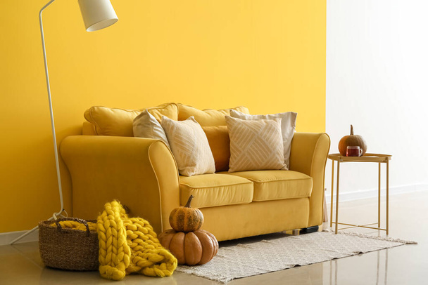Innenraum eines hellen Wohnzimmers mit gelbem Sofa und Kürbissen - Foto, Bild