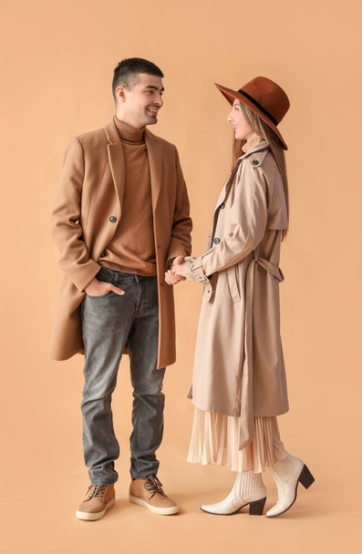 Fashionable young couple in autumn clothes on beige background - Photo, Image