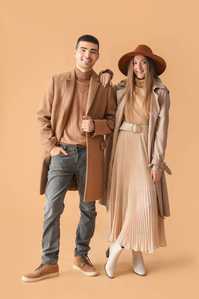 Jeune couple à la mode en vêtements d'automne sur fond beige - Photo, image