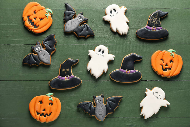 Tasty Halloween cookies on green wooden background - Foto, afbeelding
