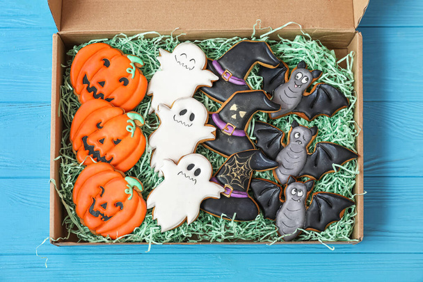 Cardboard box with Halloween cookies on blue background - Фото, изображение