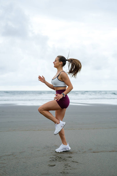 Female athlete running in place at the beach. Sporty woman on fitness outdoor workout. - Valokuva, kuva