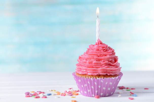 Delicious birthday cupcake on table on light blue background - Foto, imagen