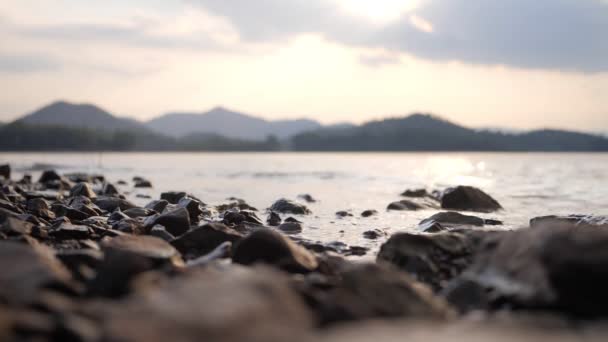 Piedras en la playa y agua de mar al atardecer - Imágenes, Vídeo