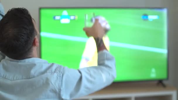 футбольный болельщик с пивом в руке смотрит чемпионат мира дома в шрифте большой экран телевизора. Высококачественные 4k кадры - Кадры, видео