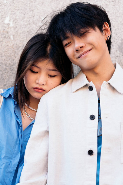 Young asian couple standing against gray wall posing and looking at camera. - Foto, afbeelding