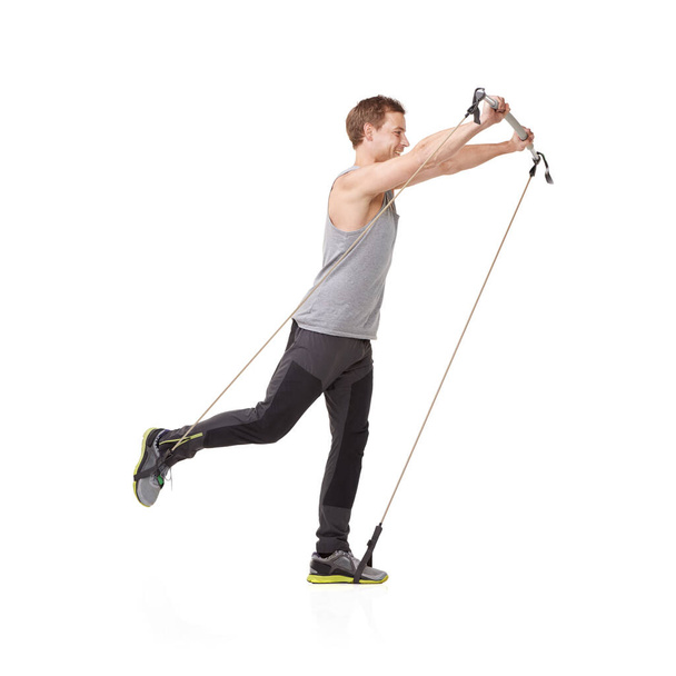 Reaching for a higher level of fitness. A young man using a resistance band to tone his body - Foto, imagen