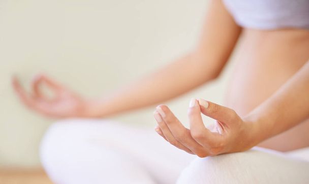 Meditieren über Mutterschaft. Ein abgeschnittenes Bild einer schwangeren Frau beim Meditieren - Foto, Bild