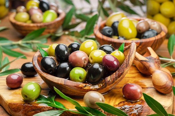 Kalamata, green and black olives in the wooden bowl. Food background. - Фото, изображение