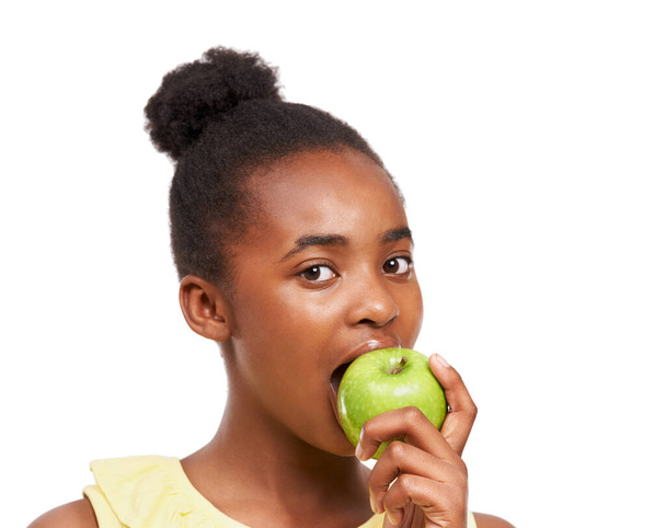 Obst ist der beste Snack. Studioporträt eines jungen afrikanisch-amerikanischen Mädchens, das einen auf Weiß isolierten Apfel isst - Foto, Bild