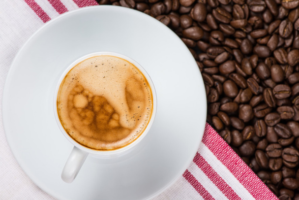 kavrulmuş kahve çekirdekleri üzerine krem espresso fincan - Fotoğraf, Görsel