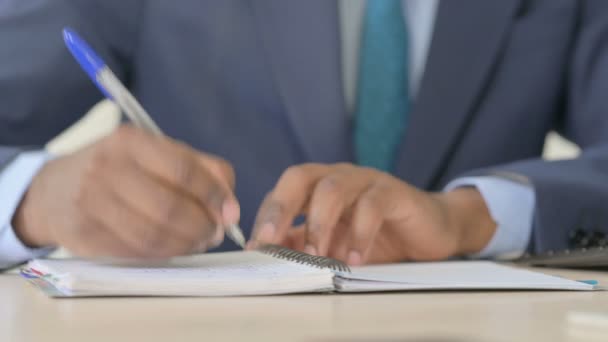 Gros plan sur l'écriture à la main d'un homme d'affaires afro-américain sur un carnet - Séquence, vidéo