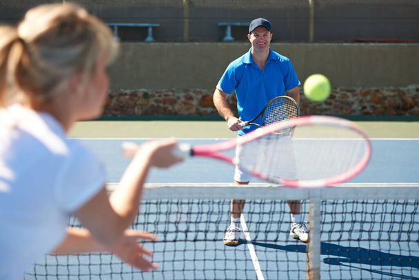 Tenis harika bir eğlence aktivitesidir. Bir bayan tenisçi tenis kortunda erkek rakibine geri vuruyor. - Fotoğraf, Görsel