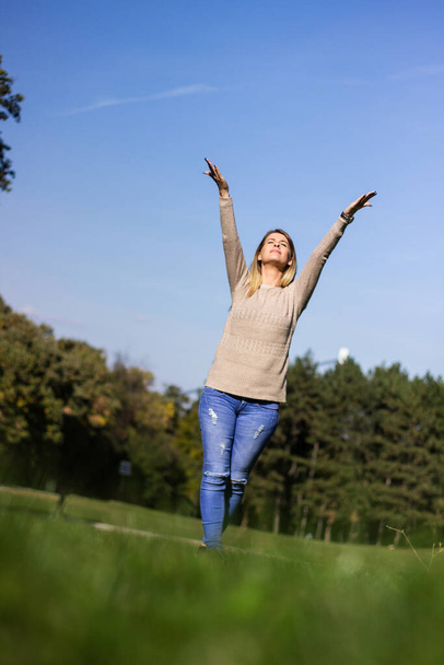 junge Frau hebt die Arme und genießt die frische Luft im grünen Wald - Foto, Bild