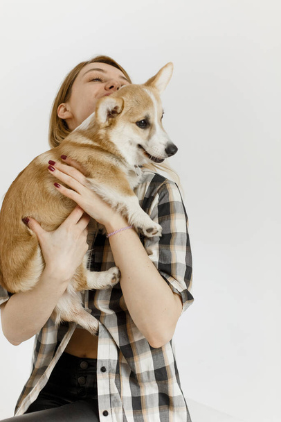 woman with a pet corgi dog plays and teaches furry friend commands inside the hous - 写真・画像