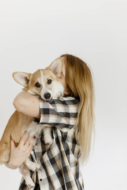 woman with a pet corgi dog plays and teaches furry friend commands inside the hous - Photo, image