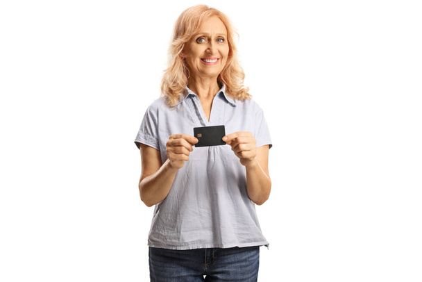 Mature woman holding a credit card and smiling isolated on white background - Foto, Imagem