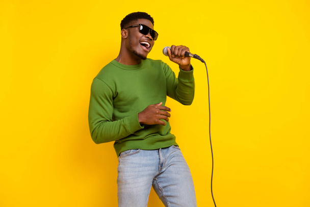 Portrait of attractive trendy cheerful guy rest free time singing single pop isolated over bright yellow color background. - Φωτογραφία, εικόνα